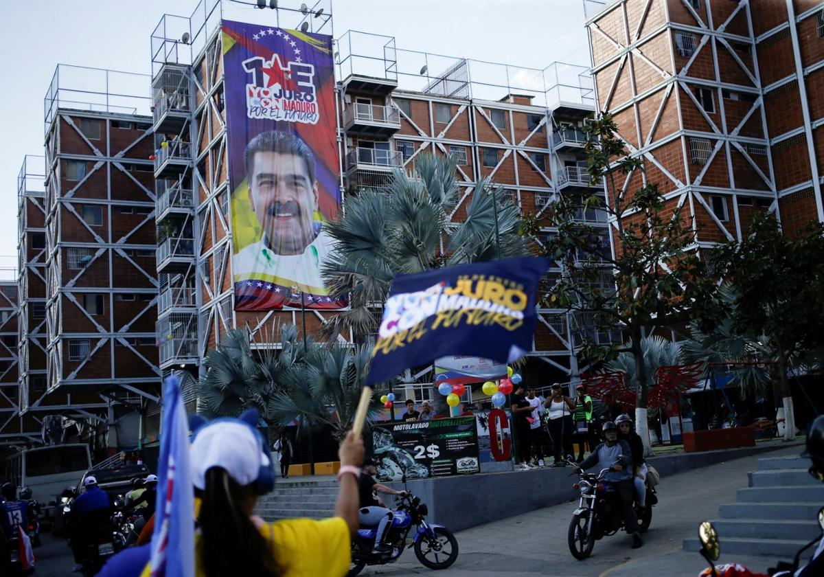 Un grupo de motociclistas pasan junto a un cartel del presidente de Venezuela, Nicolás Maduro, en una calle de Caracas.