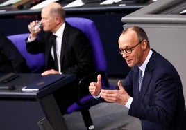 El líder de la CDU, Friedrich Merz, con Scholz al fondo, durante la polémica sesión de este miércoles en el Bundestag.