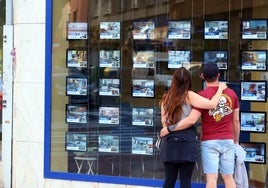 Dos jóvenes miran los carteles de una inmobiliaria en Miranda de Ebro.