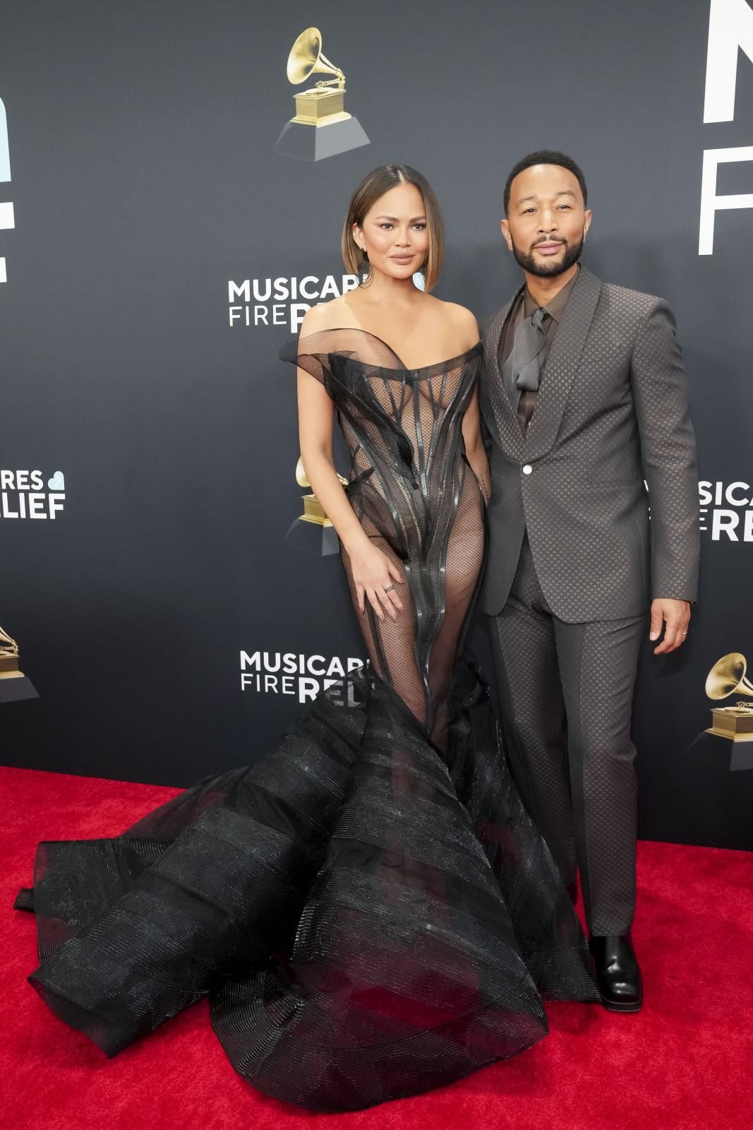 El cantante John Legend, completamente de negro, con su pareja, Chrissy Teigen, a juego con un vestido de Christian Siriano con corsé. 