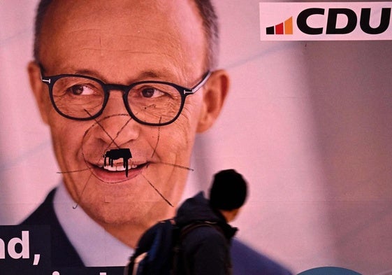 Un hombre pasa junto a un cartel de Friedrich Merz, candidato a canciller de la CDU, en Fráncfort.