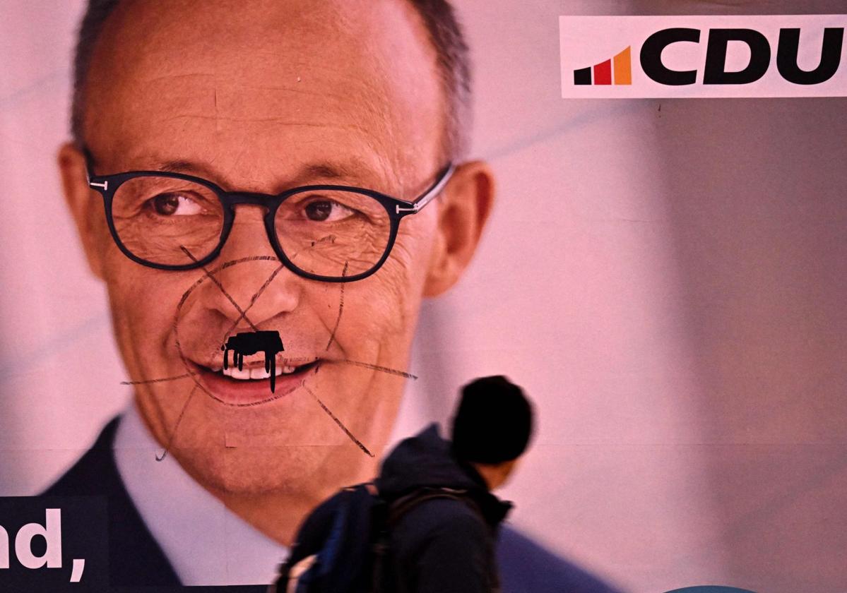 Un hombre pasa junto a un cartel de Friedrich Merz, candidato a canciller de la CDU, en Fráncfort.