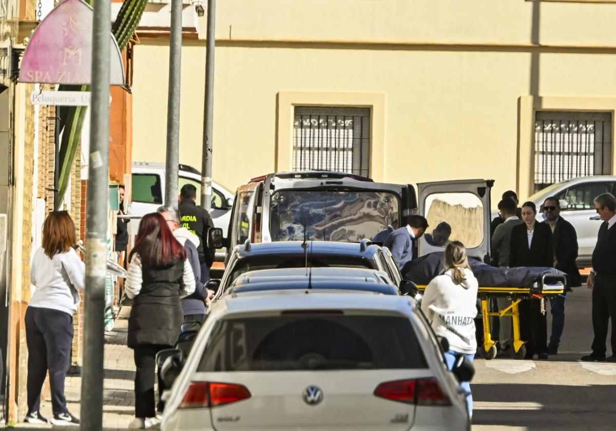 Empleados de la funeraria trasladan el cuerpo sin vida de una mujer de una vivienda de la localidad sevillana de Brenes