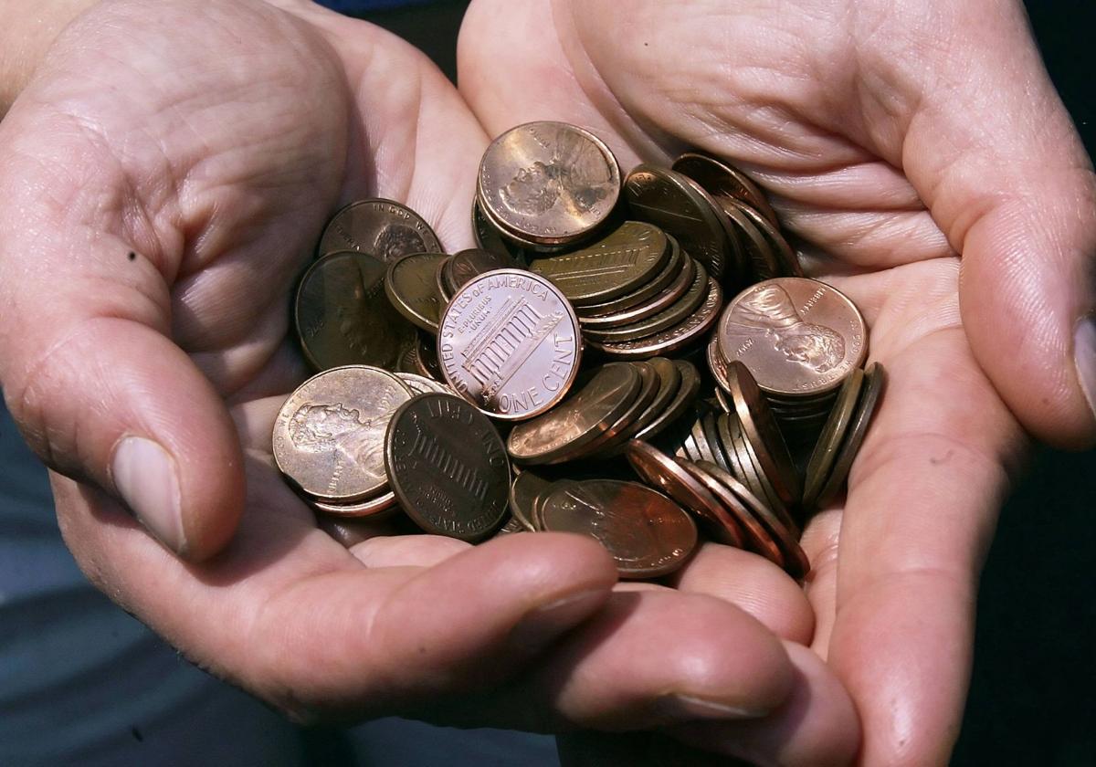 Un hombre enseña sus manos llenas de monedas de un centavo.