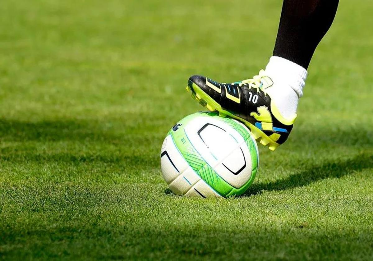 Un futbolista controla un balón.