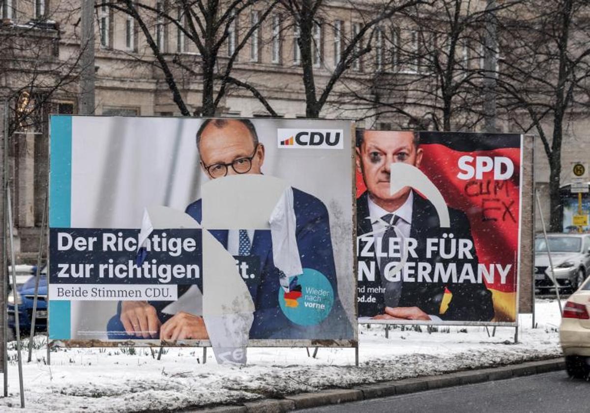 Carteles electorales dañados del actual canciller alemán, el socialdemócrata Olaf Scholz, y del líder conservador, Friedrich Merz, en una calle de Berlín.