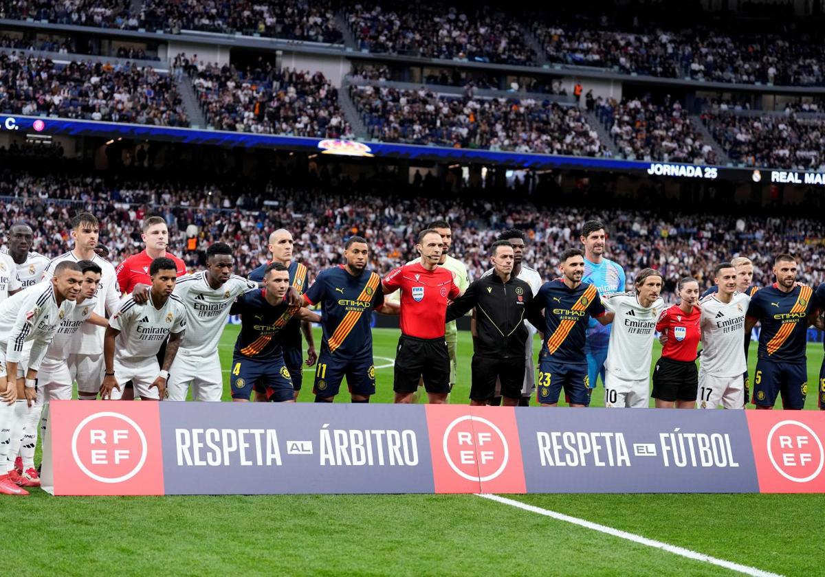 Los jugadores del Real Madrid y del Girona posan tras el cartel de apoyo al árbitro en el Santiago Bernabéu.