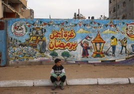 Un niño palestino se sienta frente a un mural en el campo de refugiados de Nuseirat, en el centro de la Franja.