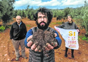 El agricultor Ángel Delgado, con un puñado de tierra del Campo de Montiel, donde una minera busca neodimio. Tras él, Raquel Pérez y Miguel Fuentes.