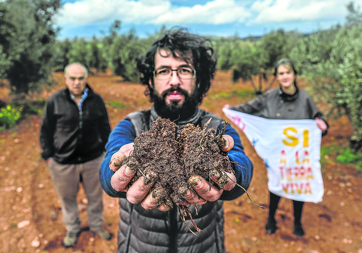 El agricultor Ángel Delgado, con un puñado de tierra del Campo de Montiel, donde una minera busca neodimio. Tras él, Raquel Pérez, portavoz de la plataforma Sí a la Tierra Viva, y Miguel Fuentes, ambos también agricultores.