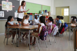 Varios alumnos en una clase atienden a una profesora