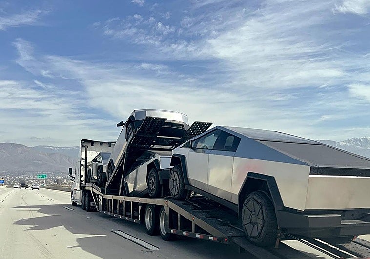Un portavehículos transporta cuatro nuevos Tesla Cybertrucks por la autopista de Highland, California