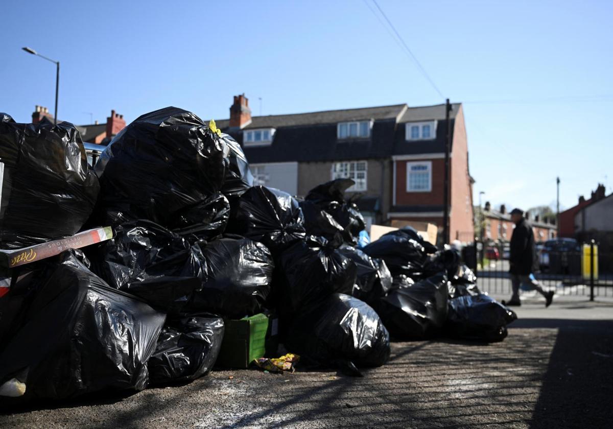 Un hombre pasa por una calle de Birmingham donde se acumulan las bolsas de basura.