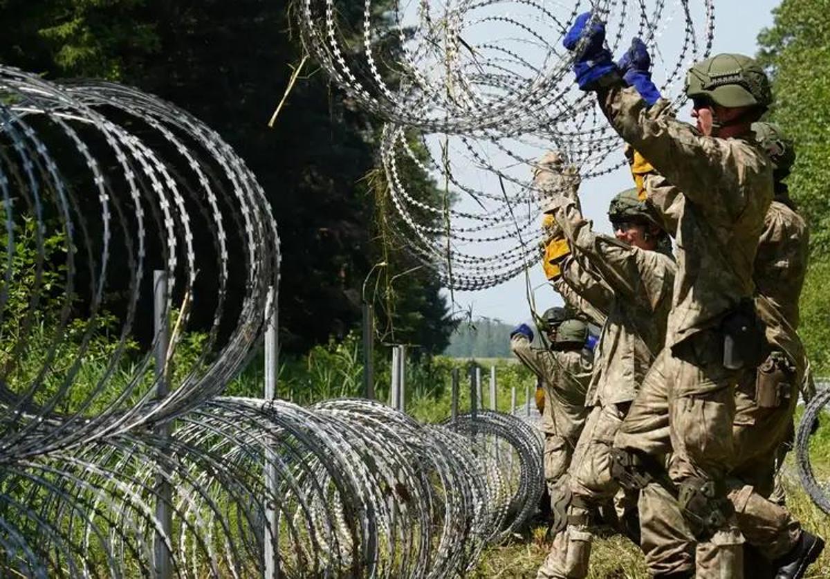 Soldados lituanos colocan alambradas para delimitar y proteger la frontera con Bielorrusia.