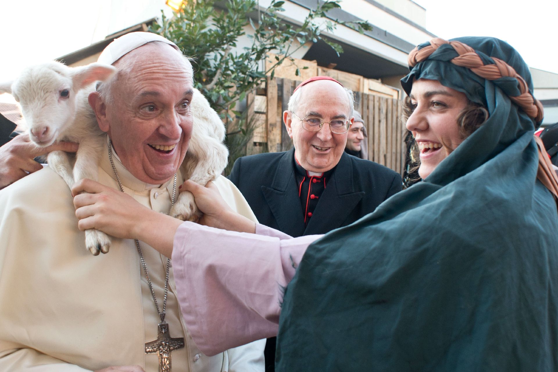 Esta fotografía difundida el 6 de enero de 2014 por la oficina de prensa del Vaticano muestra al papa Francisco (izq.) llevando un cordero sobre sus hombros mientras visita la parroquia de Sant'Alfonso Maria de Ligorio durante el día de la Epifanía en Roma.