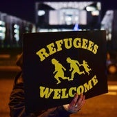 Un manifestante muestra un cartel que dice «refugiados bienvenidos» frente a una concentración de simpatizantes del partido ultraderechista AfD en Berlín.