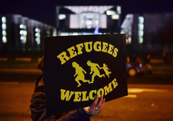Un manifestante muestra un cartel que dice «refugiados bienvenidos» frente a una concentración de simpatizantes del partido ultraderechista AfD en Berlín.