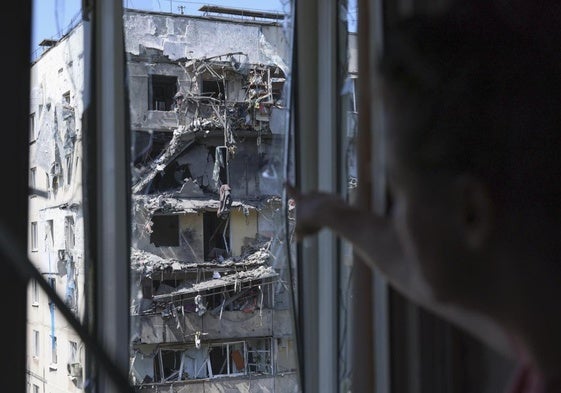 Una mujer muestra los daños de un edificio vecino bombardeado por el ejército ruso en Zaporiyia.