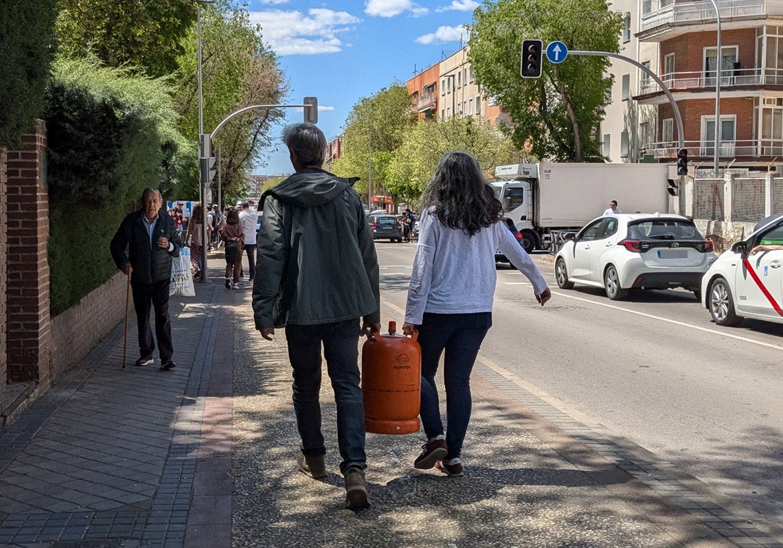Una pareja transporta una bombona de gas que acaba de conseguir en la gasolinera.