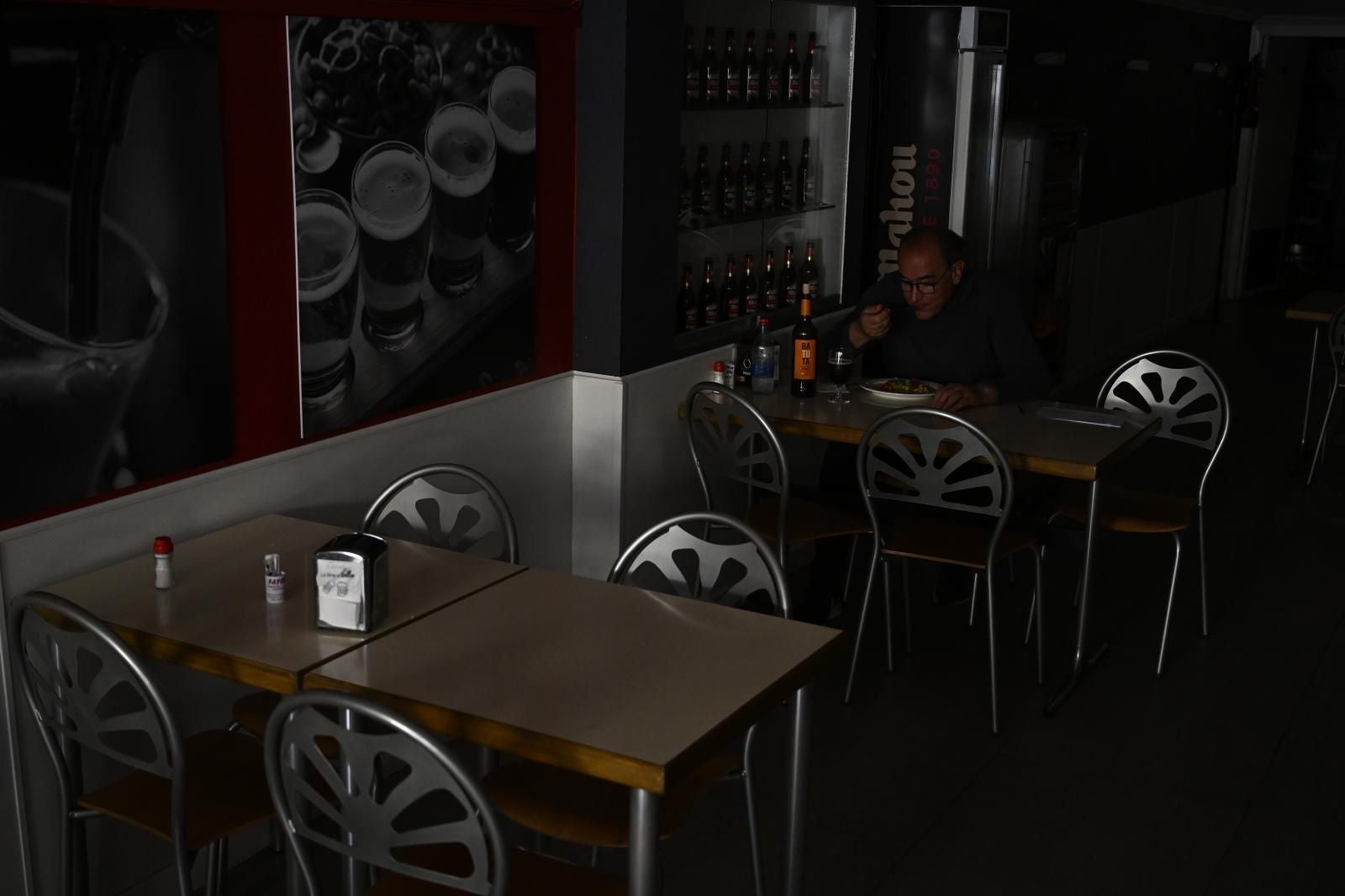 Un hombre come en un restaurante apagado por el corte del suministro eléctrico