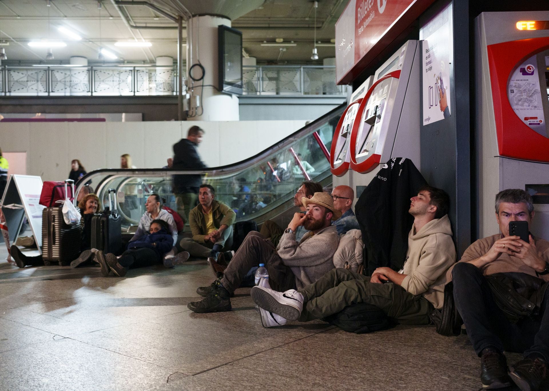 Pasajeros esperan noticias en el suelo de la estación de Atocha., 