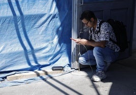 Un joven carga su móvil con una batería solar