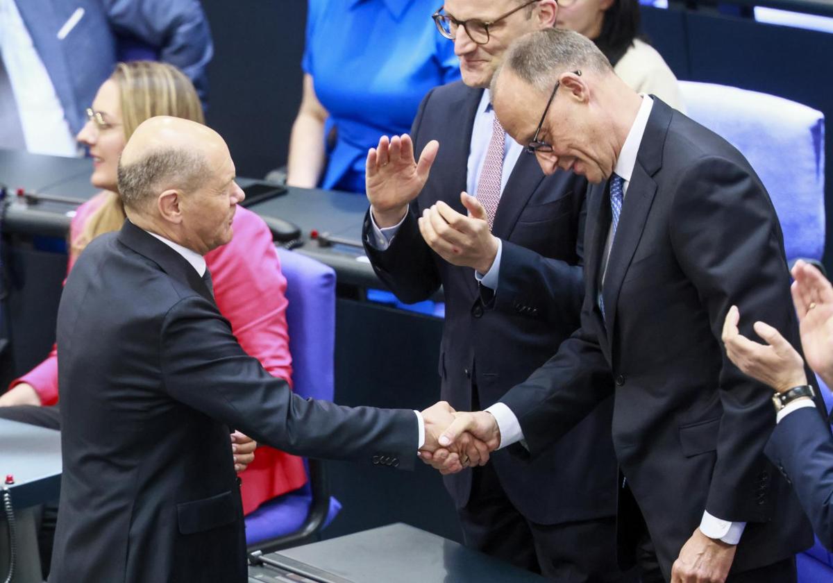El socialdemócrata Olaf Scholz (izquierda) felicita a su sucesor al frente de la cancillería, el conservador Friedrich Merz, tras su investidura ayer en el Bundestag.