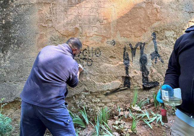 Técnicos de la Alhambra limpian el grafiti a primera hora de este viernes.