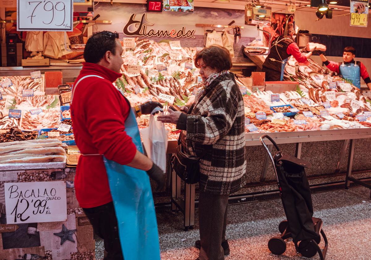 Una mujer recoge su compra en la pescadería.