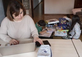 Una madre teletrabajando mientras sus tres hijos juegan.