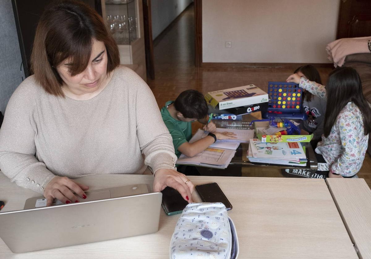 Una madre teletrabajando mientras sus tres hijos juegan.