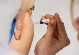 Una sanitaria vacuna a un niño contra el sarampión.