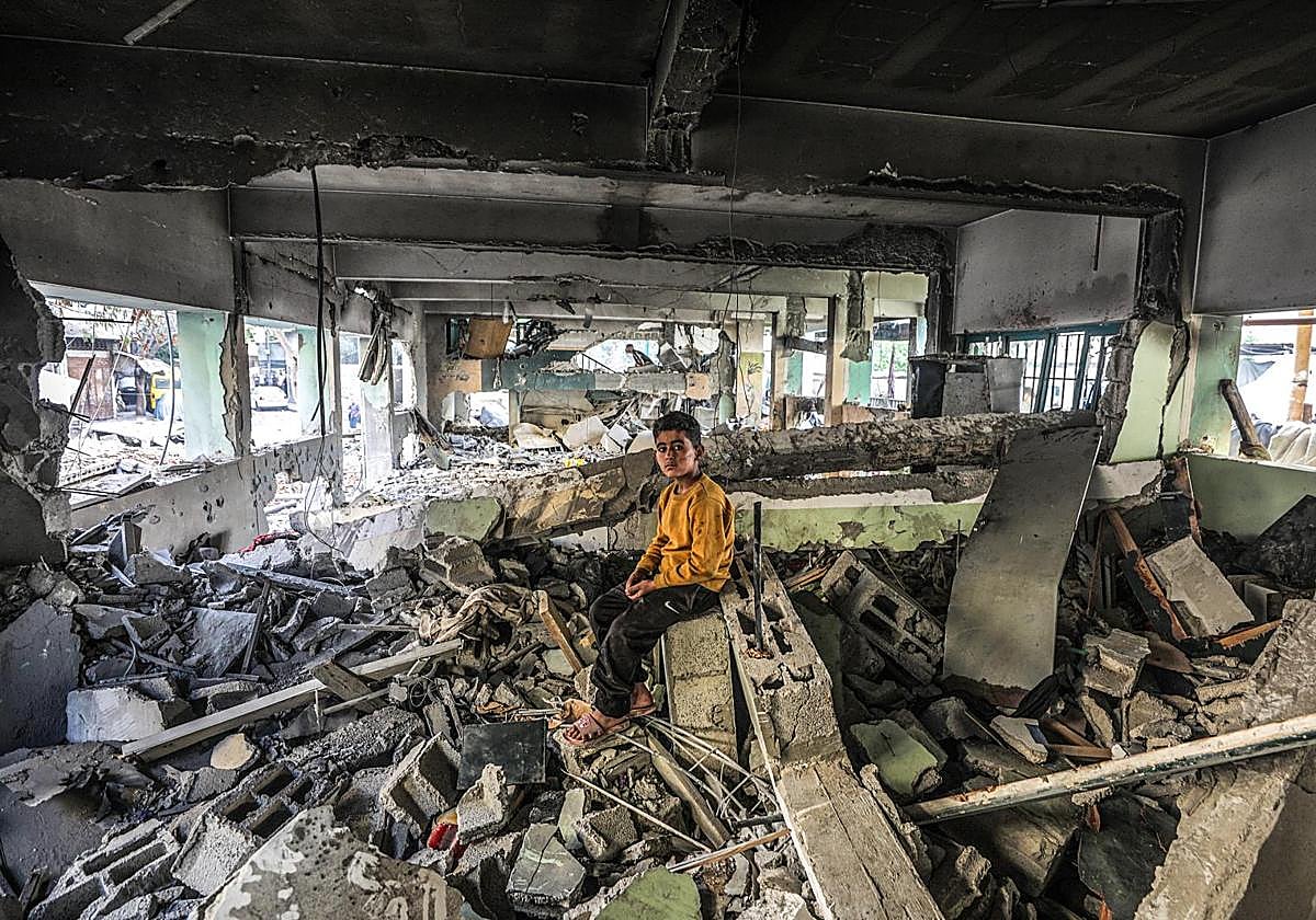 Un niño permanece sentado entre las ruinas del colegio bombardeado en Gaza City donde murieron 36 civiles, 18 de ellos menores.