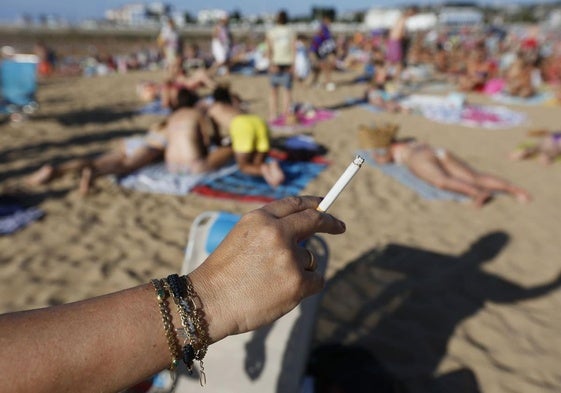 Una mujer fuma en una playa.