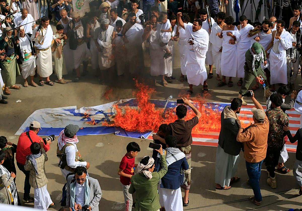 Yemeníes queman banderas de Israel y Estados Unidos durante una manifestación en solidaridad con Gaza en la capital gobernada por los hutíes, Saná.