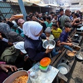 Un grupo de palestinos espera a recibir comida en un punto de distribución en Nuseirat, en el centro de Gaza.
