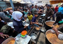 Un grupo de palestinos espera a recibir comida en un punto de distribución en Nuseirat, en el centro de Gaza.