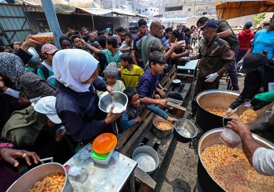 Un grupo de palestinos espera a recibir comida en un punto de distribución en Nuseirat, en el centro de Gaza.