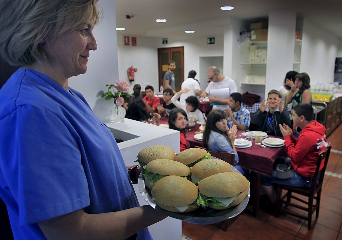 Una trabajadora sirve la comida a los menores que participan en una colonia estival.