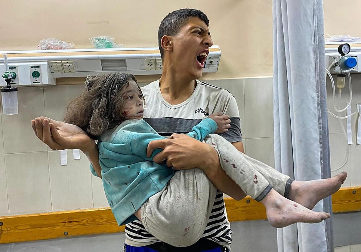 Un hombre palestino corre hacia una niña herida en los ataques israelíes contra tiendas de campaña para desplazados en Khan Yunis.