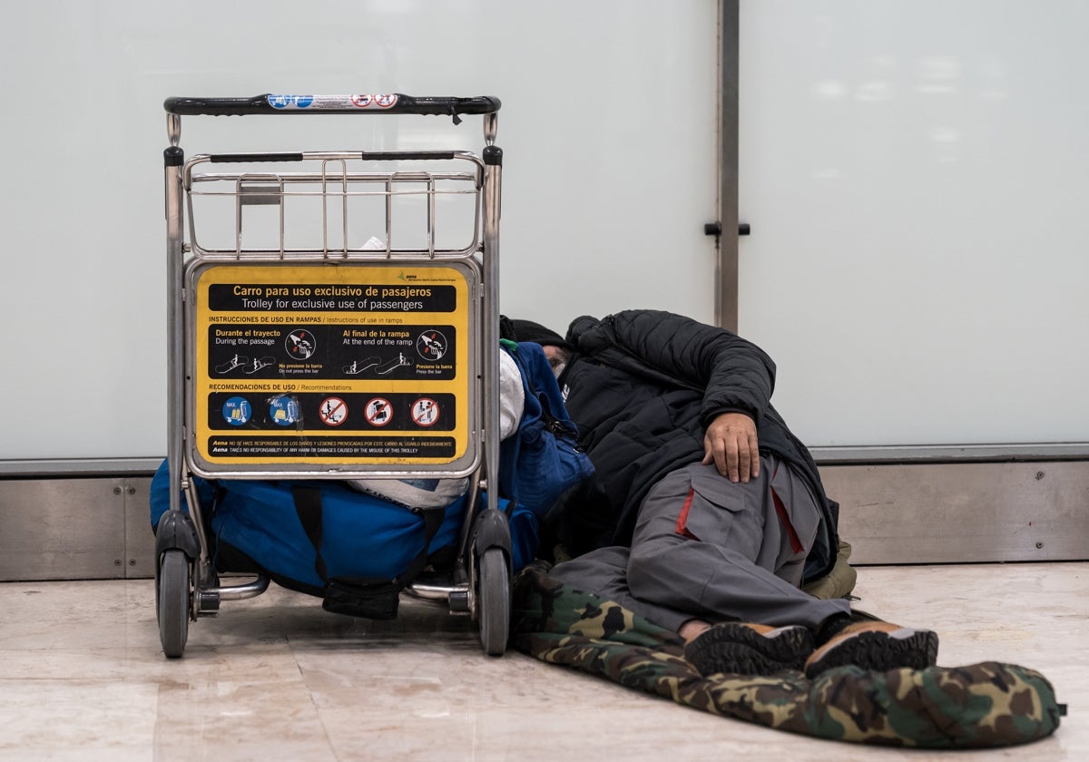 Un sinhogar duerme en el suelo de la terminar aérea madrileña de Barajas.