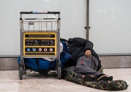 Un sinhogar duerme en el suelo de la terminar aérea madrileña de Barajas.