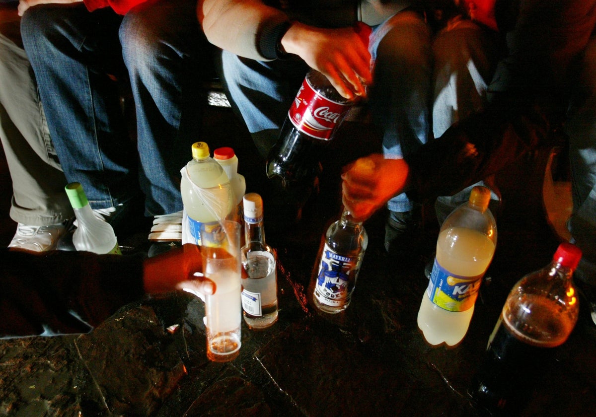 A group of young people participate in a drinking session in a park.