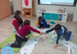 Una monitora y unos niños trabajan en un centro de atención temprana.