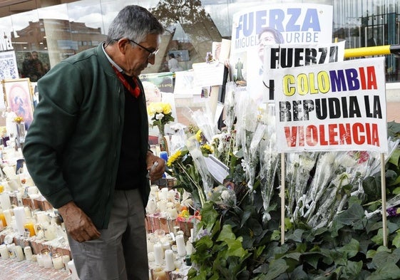 Un hombre observa un altar por Uribe Turbay frente a la Fundación Santa Fe de Bogotá.
