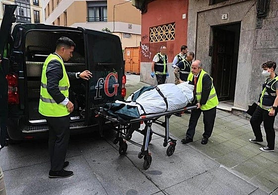 Los servicios sanitarios trasladan el cadáver de la mujer en presencia de la Policía Nacional, en la calle Contracay