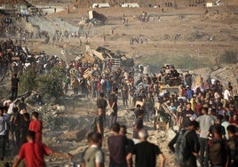 Decenas de gazatíes se congregan en torno a un punto de reparto de ayuda humanitaria.