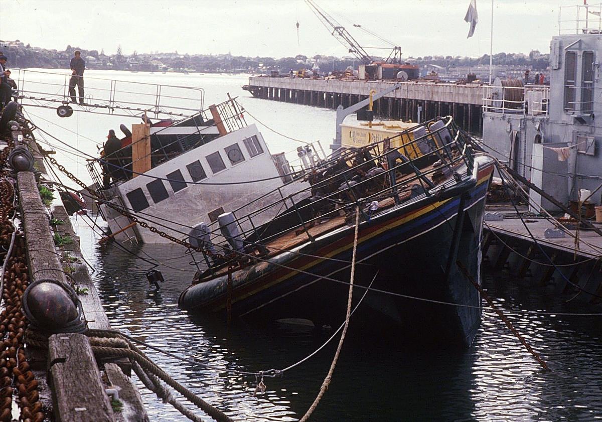 Imagen principal - Arriba, una imagen del Rainbow Warrior hundido. Fotograma del juicio a los comandos franceses yFernando Pereira, el fotógrafo que murió en el atentado.