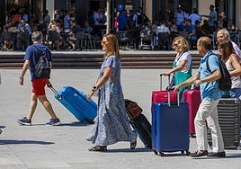 Turistas con maletas por la ciudad.
