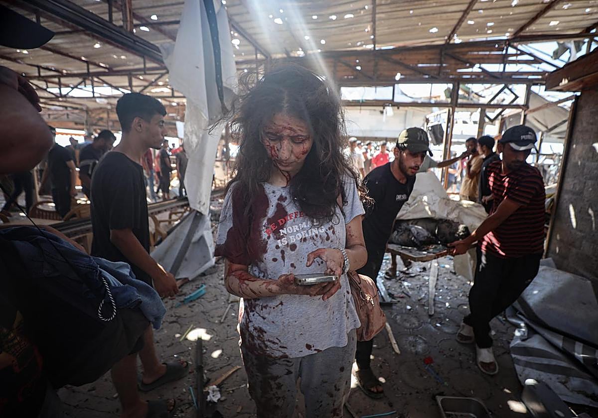 Una mujer palestina herida mira su teléfono móvil en una cafetería de Ciudad de Gaza bombardeada por el ejército israelí.